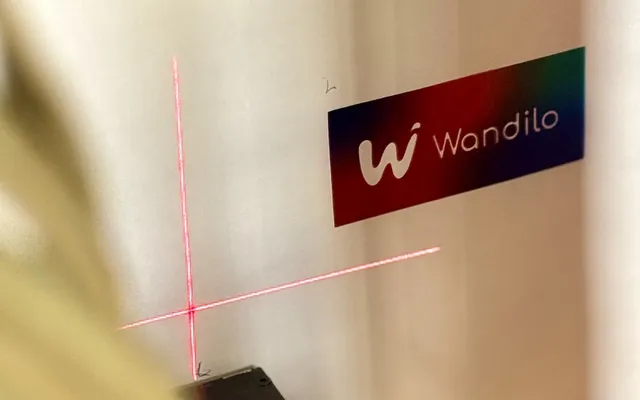 De muurprinter lijnt zich met een laserkruis uit naast een verse print van het Wandilo-logo