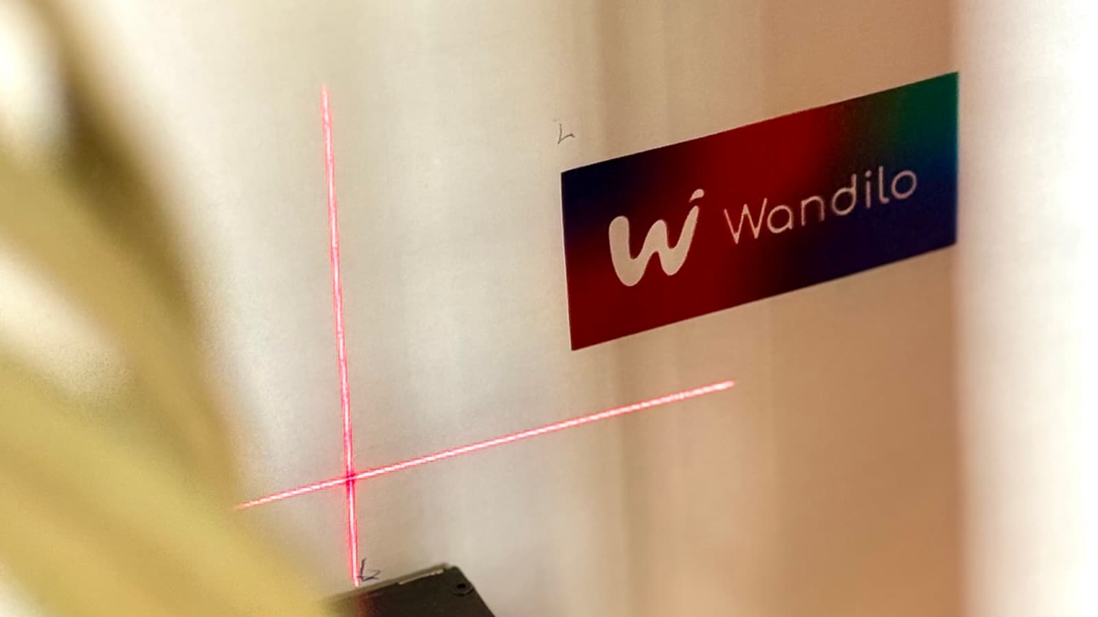 De muurprinter lijnt zich met een laserkruis uit naast een verse print van het Wandilo-logo